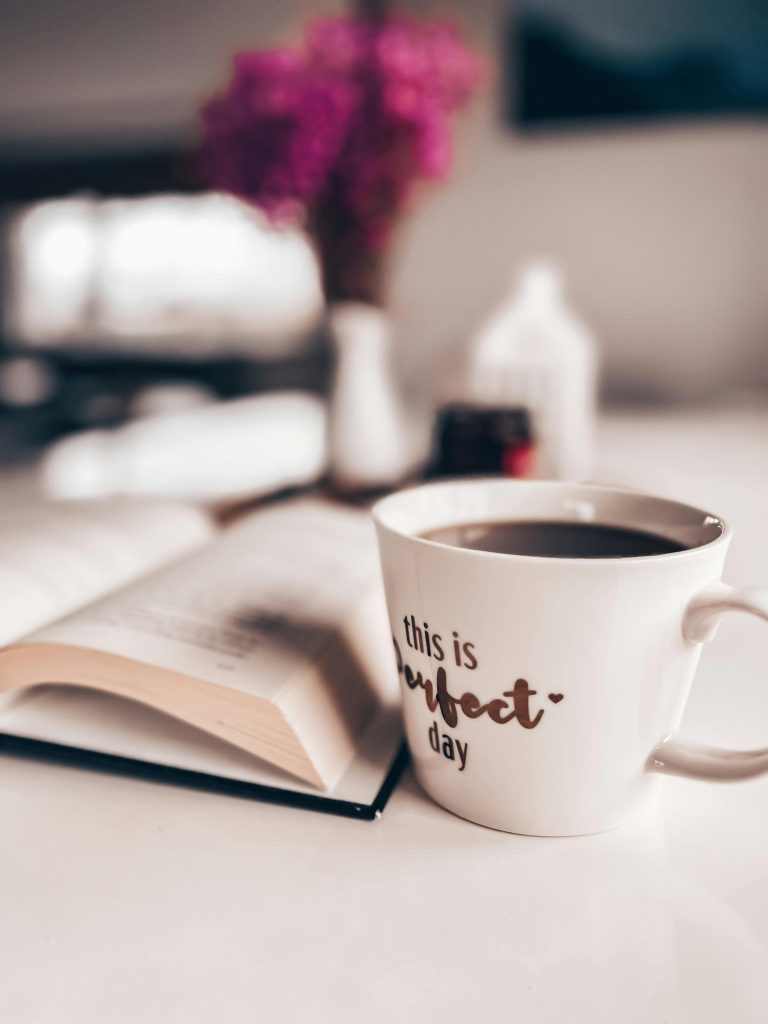 A warm cup of coffee next to an open book, perfect for a cozy morning read.